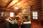 Living area, fireplace, couch, heavy beams, authentic cabin. 
